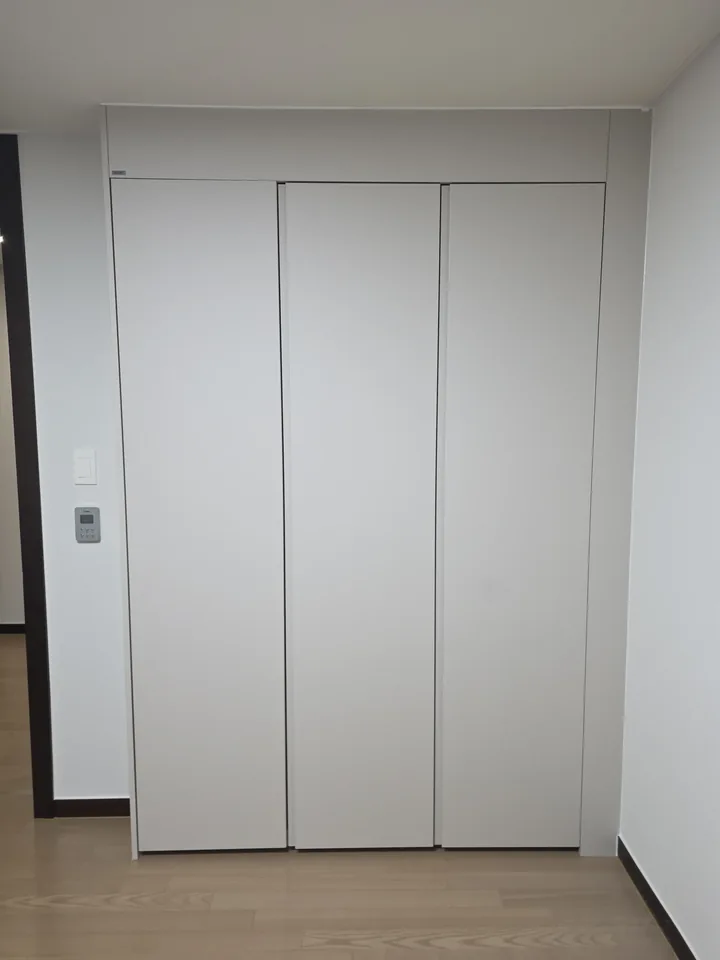 벽면 전체를 흰색 3짝 도어로 정리한 붙박이장